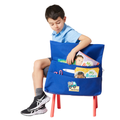 7 year old child model in school uniform sitting on a chair with the Harlequin Chair bag in royal blue over the back of the chair. The view displays personalisation and a name bar on the chair bag alongside books and scissors packed into the pockets.