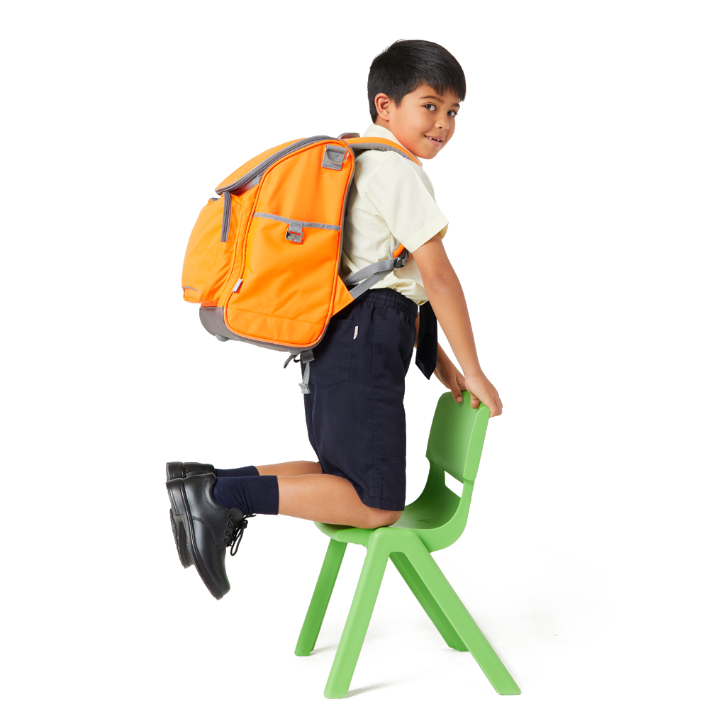 7 Year old child model wearing a school uniform, kneeling on a green plastic school chair. He has on his back the Harlequin Mighty Hi-Viz Orange Tuff-Pack Backpack.