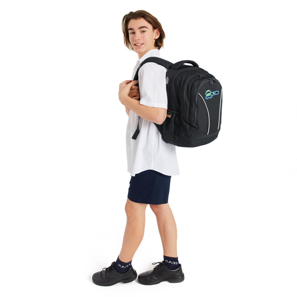 14 year old child model in school uniform walking sideways, wearing on his left shoulder the Harlequin Anatomic Large Backpack in black with personalisation.