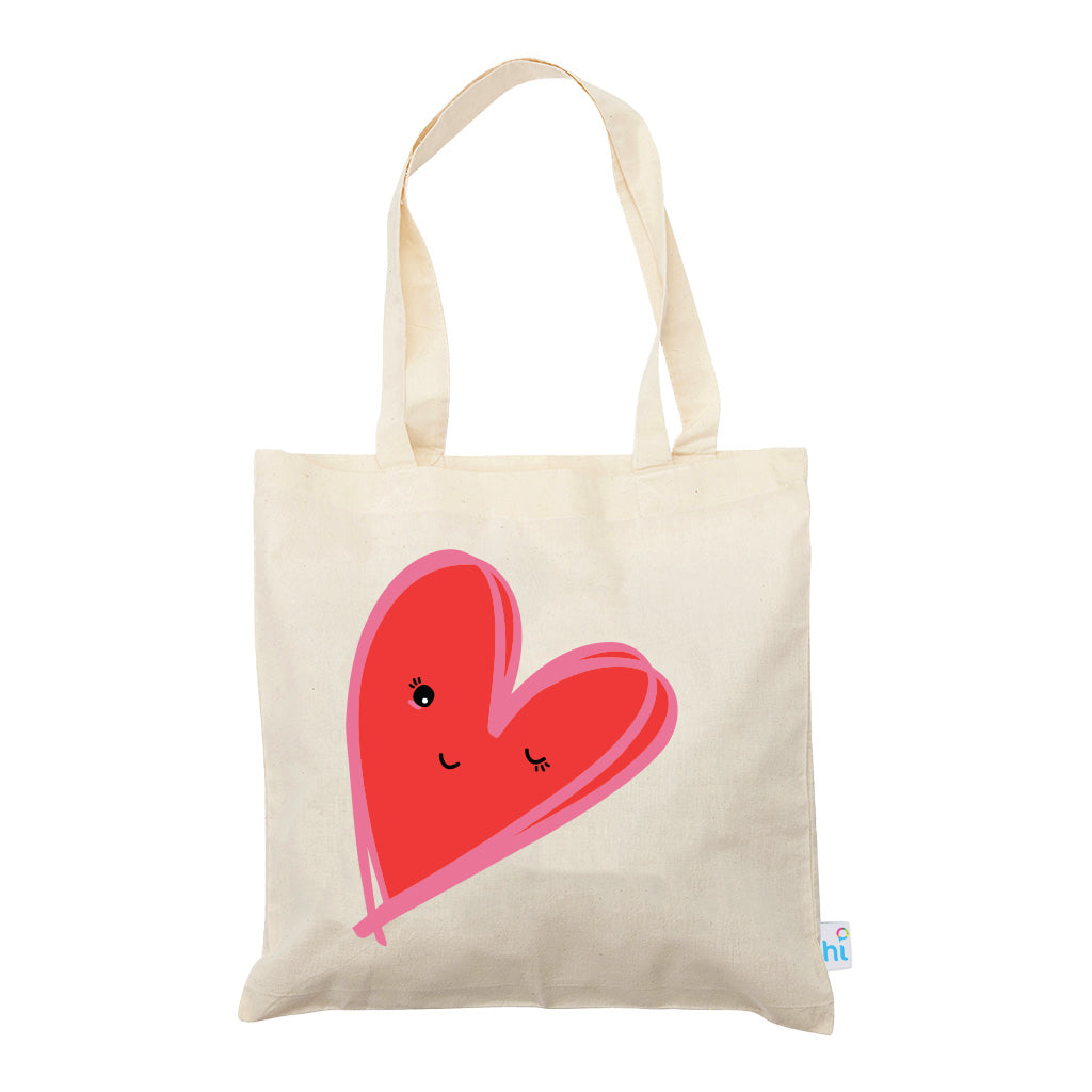 Harlequin Calico bag in natural colour displaying long shoulder handles with large red heart design