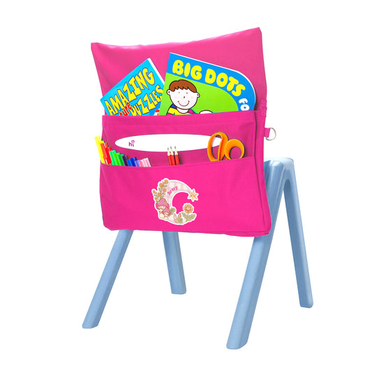 Back angle view of the Harlequin Chair Bag in pink with personalisation. View displaying two pockets, D-Ring and name bar, as well as books, scissors, pens and pencils packed into the pockets.