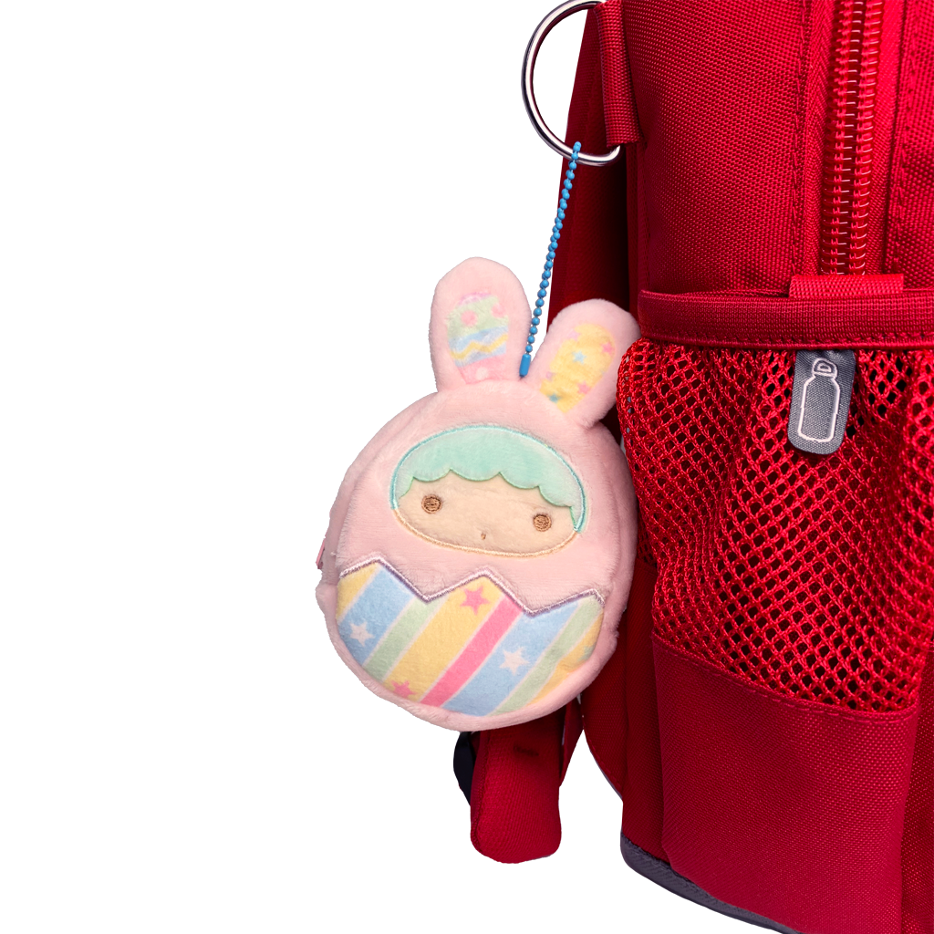 Pink character keychain attached to a red backpack