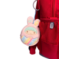 Pink character keychain attached to a red backpack
