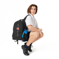 14 year old child model in a school uniform crouches. He is wearing on his right should the Harlequin Quantum Large Daypack in black with personalisation. 