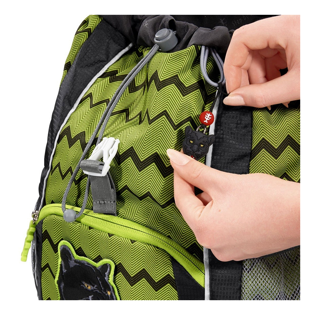 Green and black zigzag patterned backpack with a hand adjusting a strap.